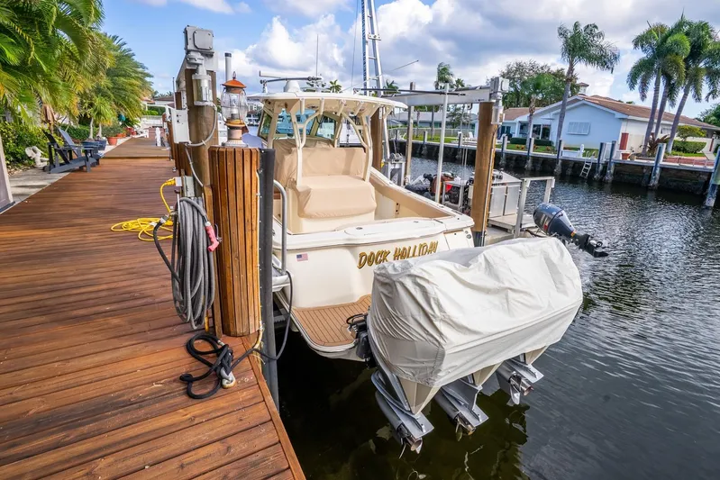  Yacht Photos Pics 2020 Scout 355 LXF boat docked by a wooden pier with palm trees.