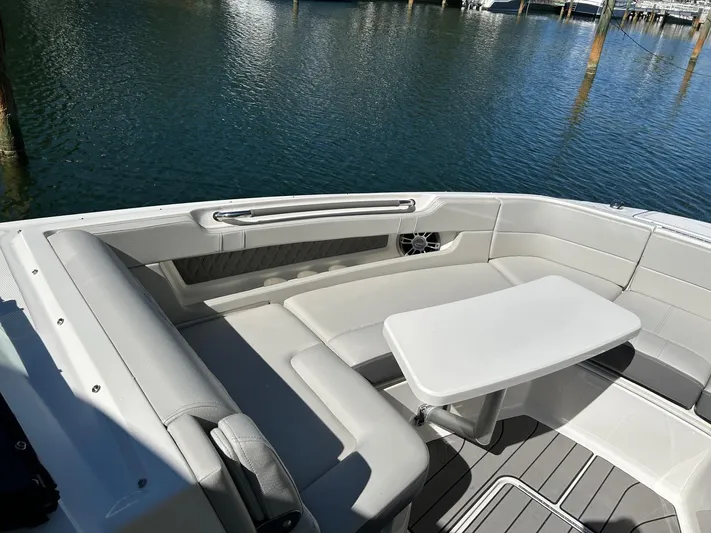  Yacht Photos Pics 2023 Sea Ray SLX 310 OB boat with elegant seating and table, docked by the water.