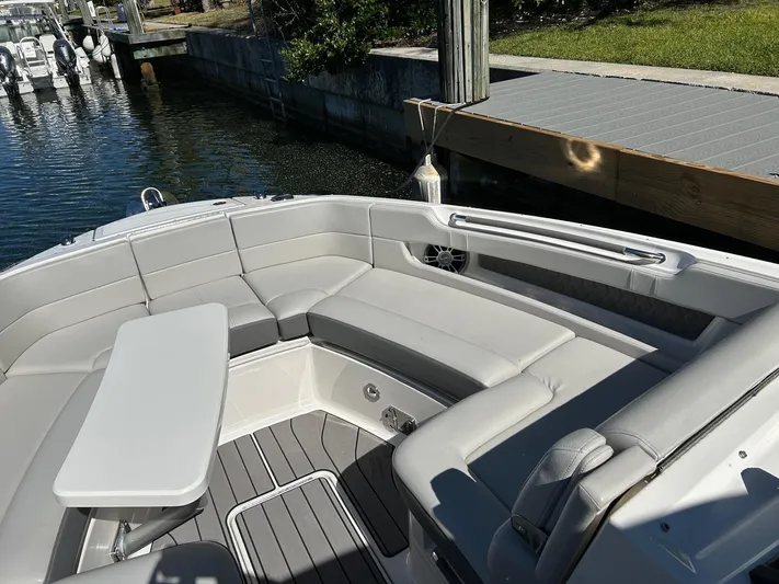  Yacht Photos Pics 2023 Sea Ray SLX 310 OB boat interior with gray seating and table, docked by water.
