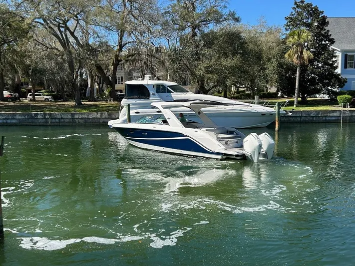  Yacht Photos Pics 2023 Sea Ray SLX 310 OB boat cruising in a scenic, tree-lined waterway.