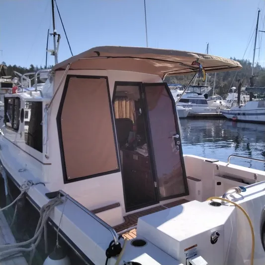  Yacht Photos Pics 2023 Ranger Tugs R-25 docked at a marina, rear view with canopy and open door.