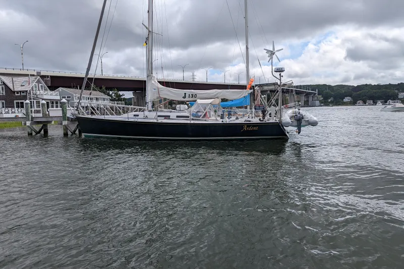 Ardent Yacht Photos Pics Sailboat J/130 from 1993 docked near a bridge under cloudy skies.