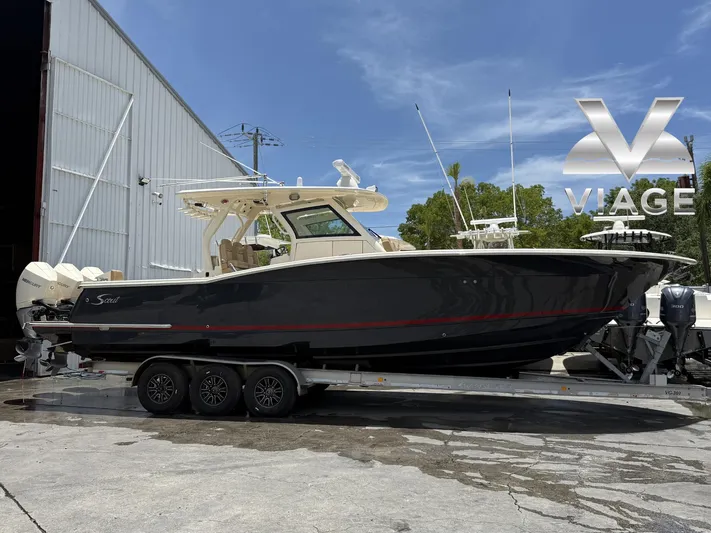  Yacht Photos Pics 2020 Scout 355 LXF boat on trailer outside a warehouse under clear blue sky.