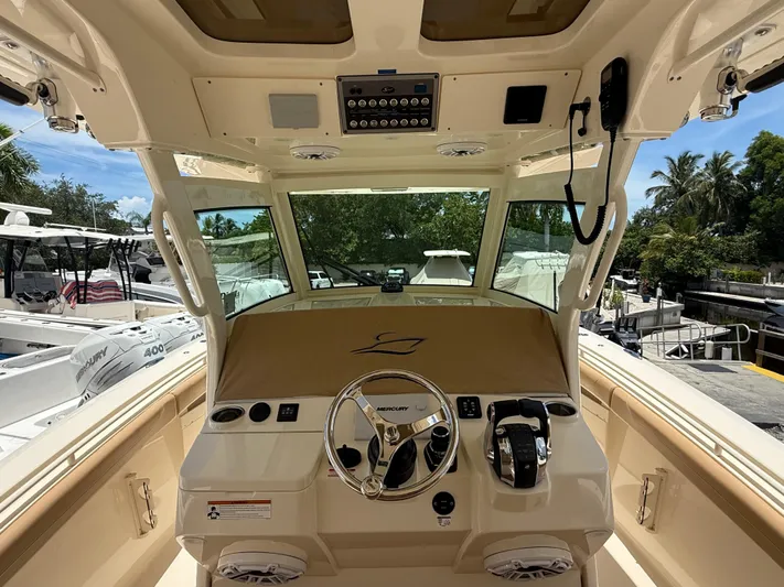  Yacht Photos Pics 2020 Scout 355 LXF boat helm with steering wheel and controls, docked near other boats.