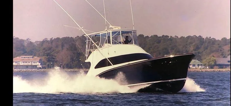  Yacht Photos Pics 1969 Hatteras 45 Sportfish yacht cruising on water with trees in the background.