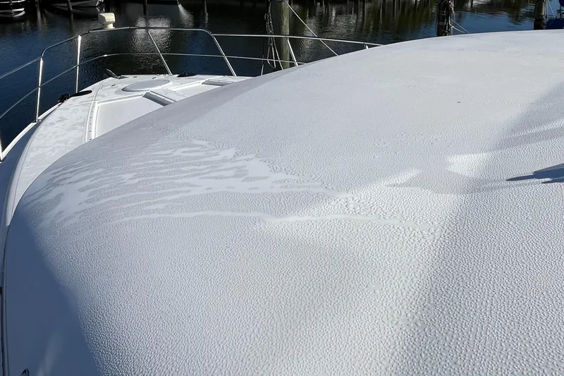 Two Can Do It Yacht Photos Pics Cruisers Yachts 4450 (2000) deck with water droplets, docked in marina.