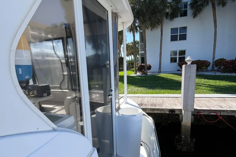 Two Can Do It Yacht Photos Pics Cruisers Yachts 4450, 2000 model, docked near a waterfront property with palm trees.