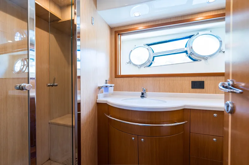 Jasmine 3 Yacht Photos Pics Luxurious bathroom interior of 2011 Apreamare Maestro 65 yacht with wooden cabinetry and porthole window.