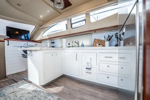 Lunasea Yacht Photos Pics Luxurious 2005 Cruiser Yachts 405 EXPRESS interior kitchen with modern white cabinetry and wood flooring.