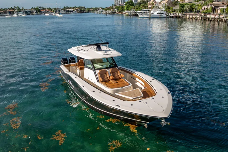  Yacht Photos Pics 2021 Scout 380 LXF boat cruising in clear blue waters near a coastal area.