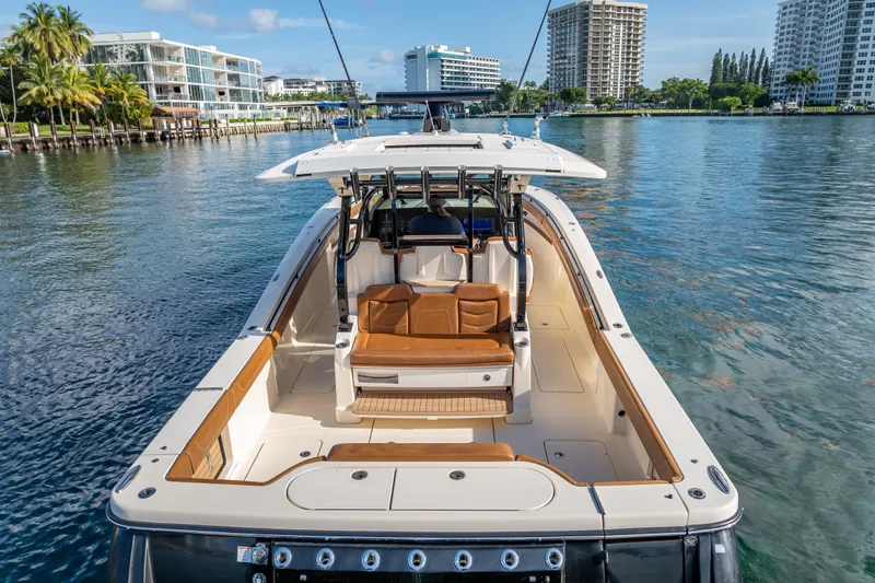  Yacht Photos Pics 2021 Scout 380 LXF boat on calm water, surrounded by modern buildings and palm trees.