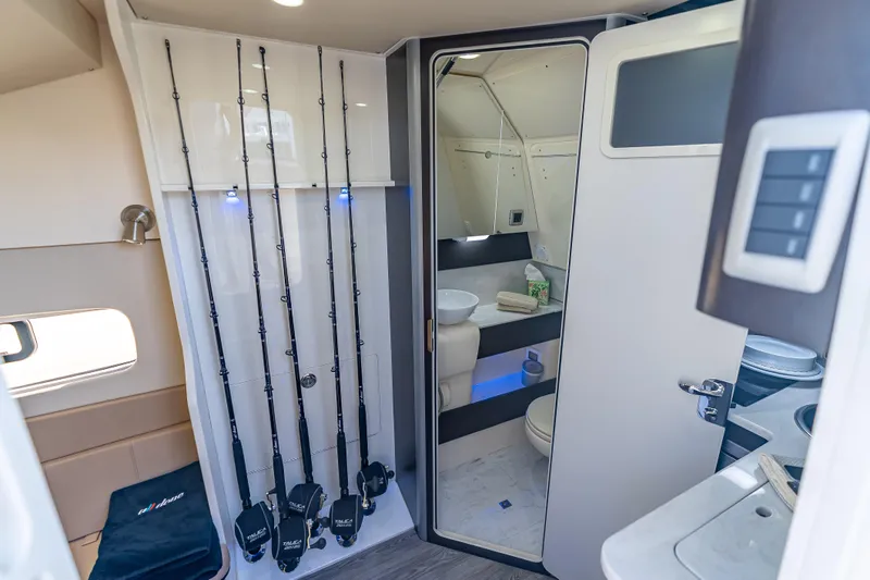  Yacht Photos Pics Interior of 2021 Scout 380 LXF boat featuring fishing rods and modern bathroom amenities.