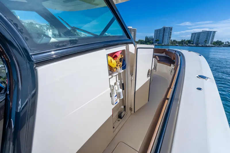  Yacht Photos Pics 2021 Scout 380 LXF boat interior with storage compartment open, docked near waterfront buildings.