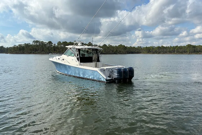 Pescador Yacht Photos Pics 2011 Pursuit OS 375 Offshore boat cruising on a calm lake under a cloudy sky.