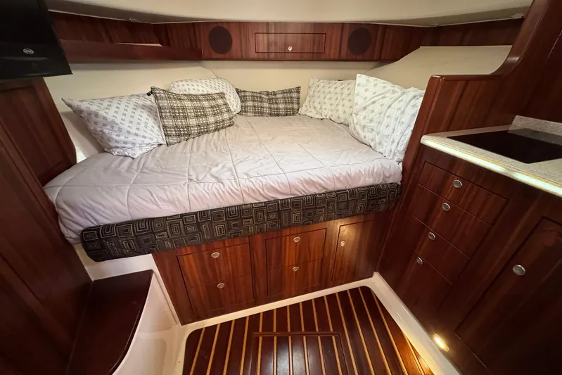 Pescador Yacht Photos Pics Luxurious cabin interior of 2011 Pursuit OS 375 Offshore with cozy bedding and wooden cabinetry.
