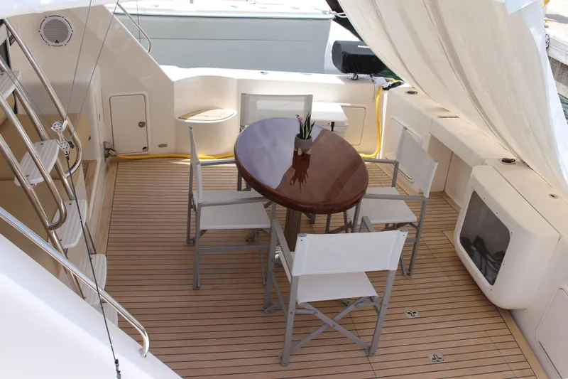  Yacht Photos Pics Outdoor seating area on a 2005 Riviera 51 Flybridge yacht with a wooden table and chairs.
