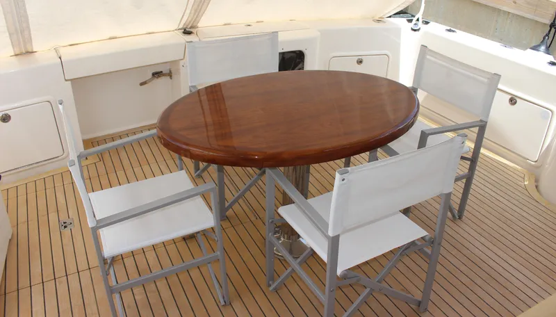  Yacht Photos Pics Outdoor dining area on 2005 Riviera 51 Flybridge yacht with wooden table and four chairs.