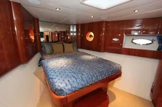Mabel Yacht Photos Pics Luxurious bedroom interior of a 2001 Precision Convertible yacht with wood paneling and porthole windows.