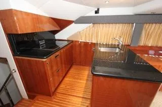 Mabel Yacht Photos Pics Luxurious kitchen area in a 2001 Precision Convertible yacht with wood cabinetry and black countertops.