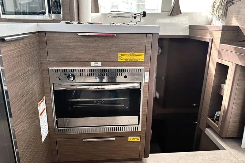 Coquina Yacht Photos Pics Modern kitchen inside 2019 Lagoon 40 catamaran with built-in oven and wooden cabinetry.
