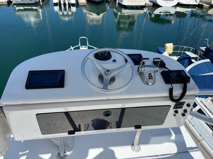 Yacht Photos Pics Helm of 2004 Cabo 35 Express boat with steering wheel and controls, docked in marina.