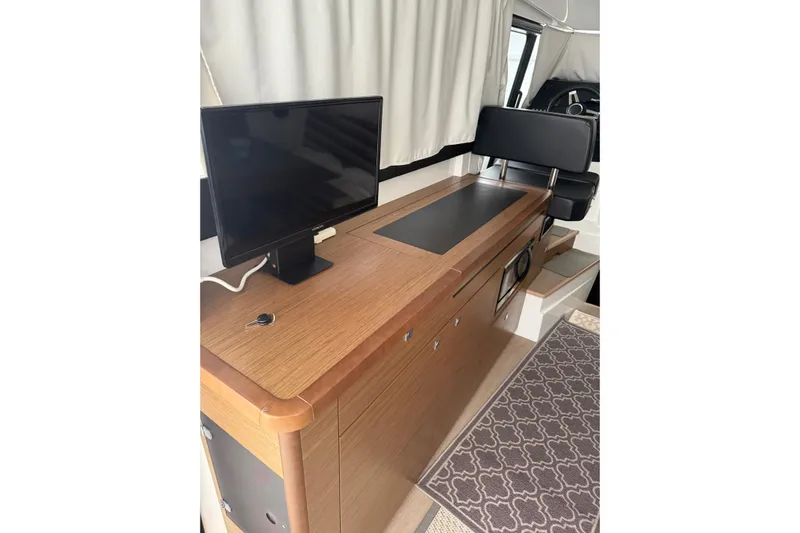  Yacht Photos Pics Interior of 2019 Jeanneau NC 9 boat with wooden cabinetry and a mounted monitor.