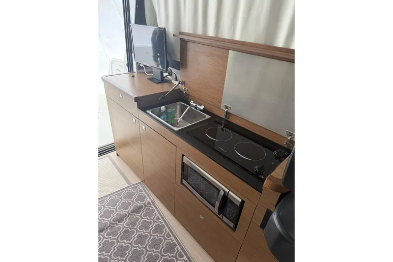  Yacht Photos Pics Compact kitchen in 2019 Jeanneau NC 9 boat with stove, sink, and microwave.