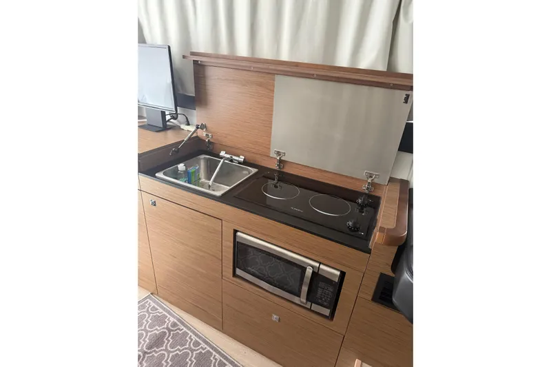  Yacht Photos Pics 2019 Jeanneau NC 9 boat kitchen with stove, sink, and microwave.