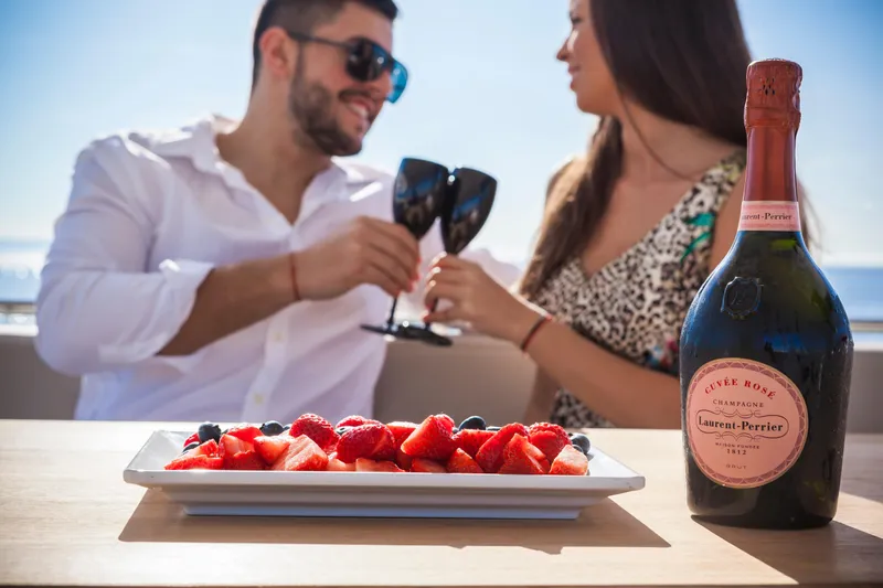Salacia Yacht Photos Pics Couple toasting with champagne on Sirena 64 yacht, enjoying strawberries and ocean view.