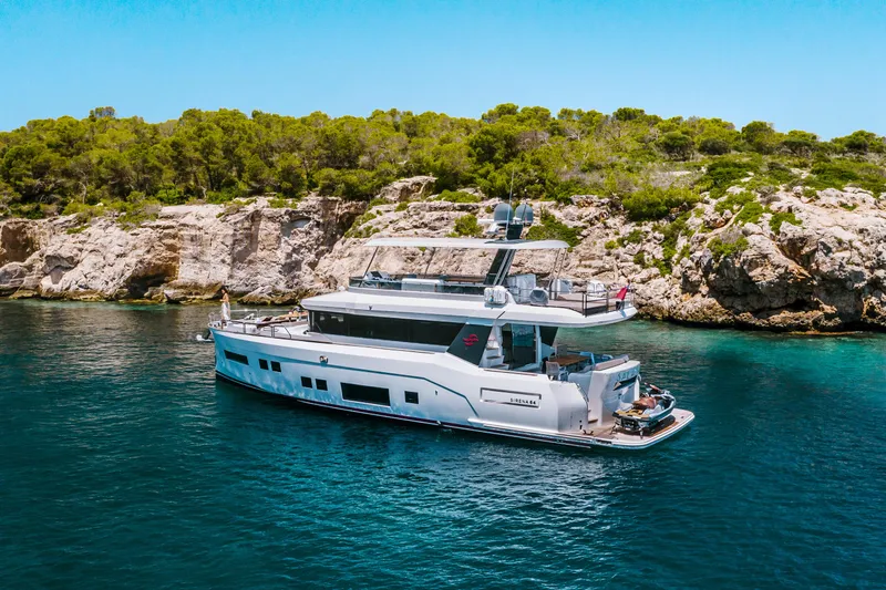 Salacia Yacht Photos Pics 2019 Sirena 64 yacht cruising near rocky coastline with lush greenery.
