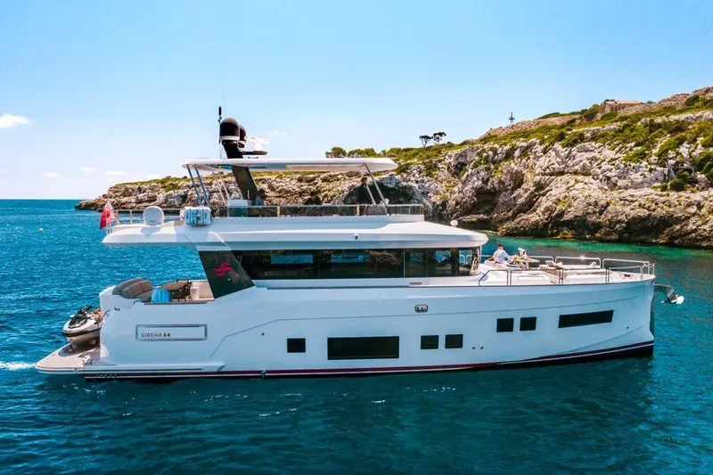 Salacia Yacht Photos Pics 2019 Sirena 64 yacht cruising near rocky coastline in clear blue waters.
