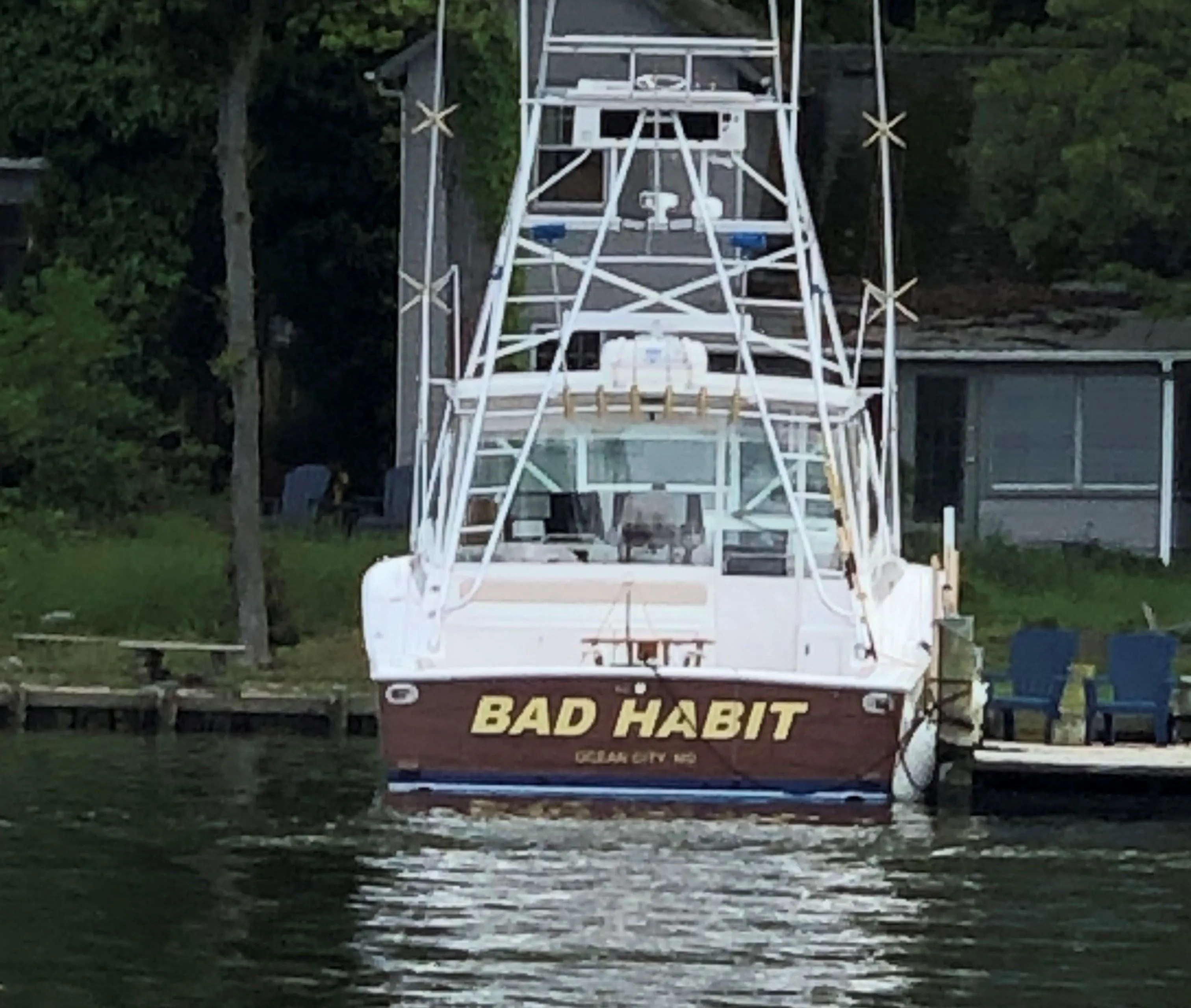 Viking 43 Open 1997 boat named "Bad Habit" docked by a lakeside.