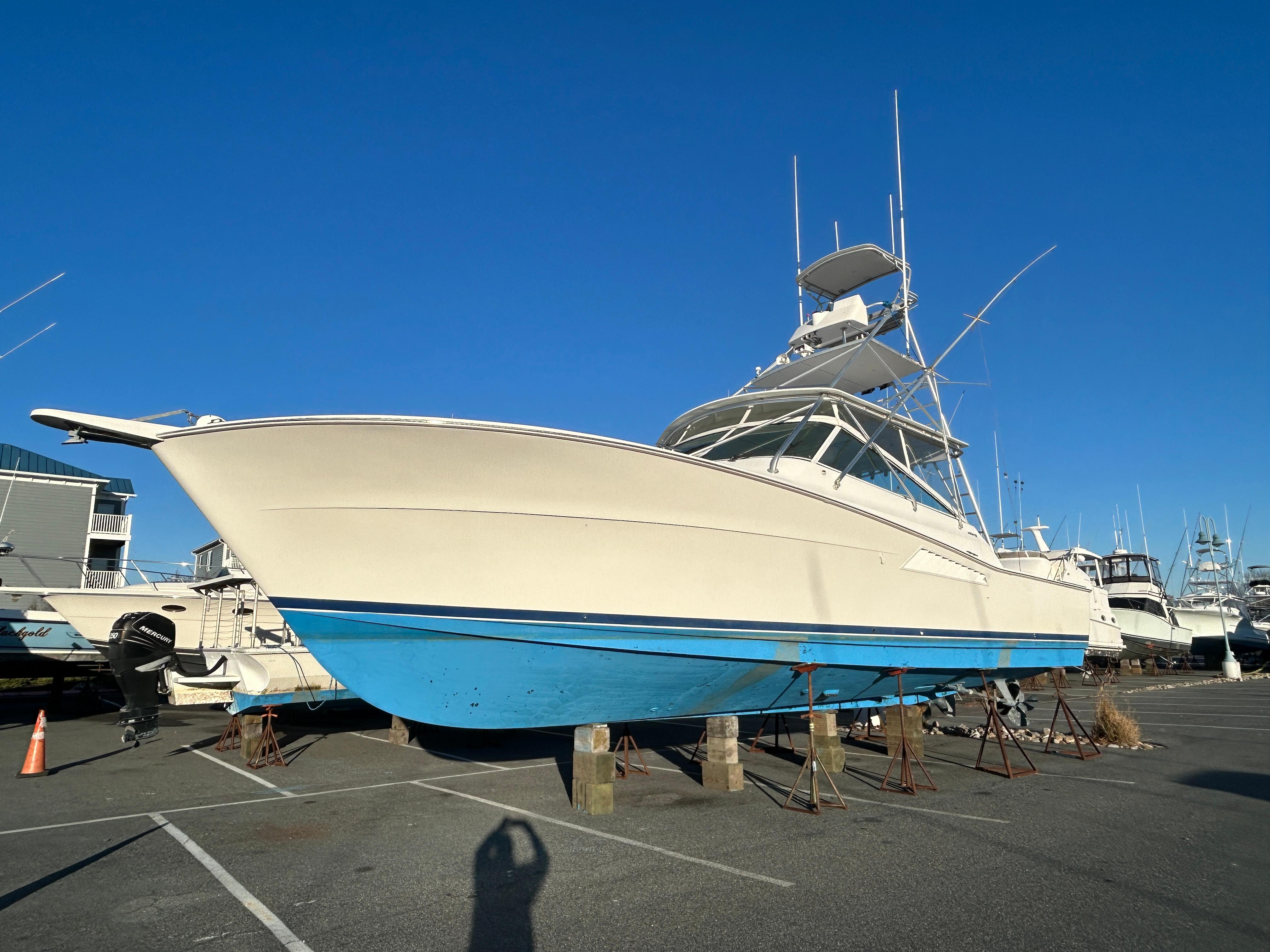 1997 Viking 43 Open boat with blue hull, docked in a marina under clear sky.
