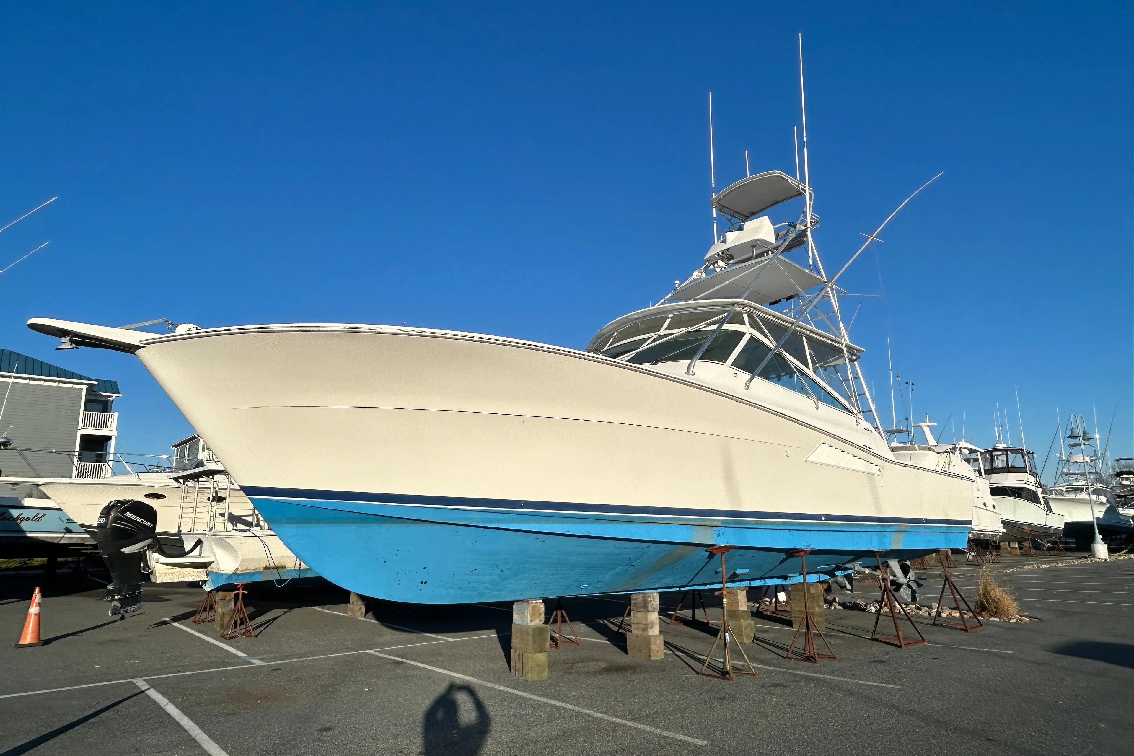 1997 Viking 43 Open boat with blue hull, docked in a marina under clear sky.