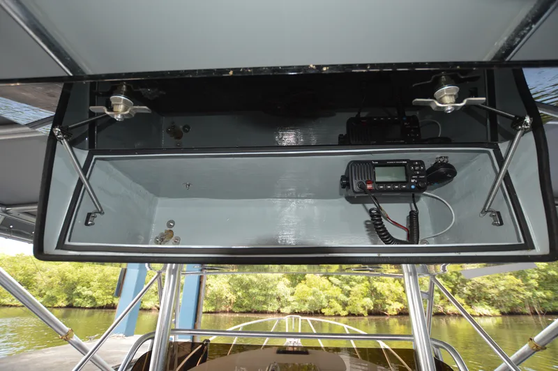  Yacht Photos Pics 2023 Strike 29 boat electronics compartment with radio, open storage, and scenic waterway view.