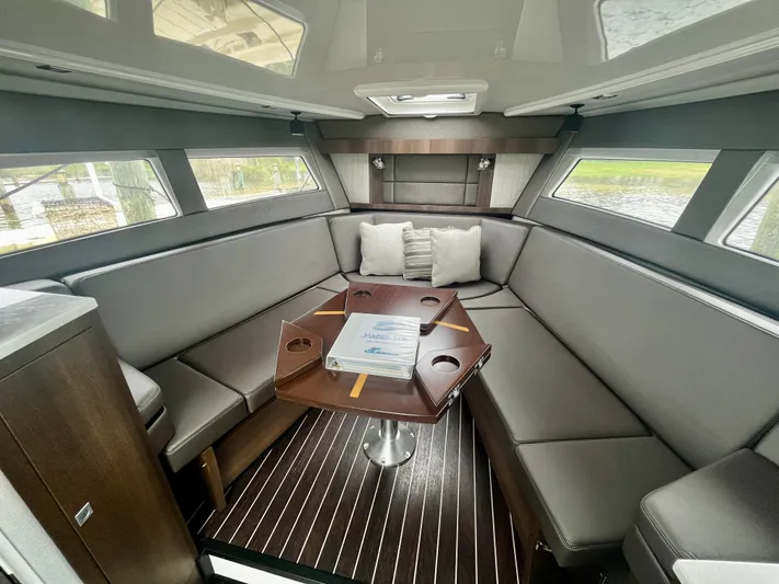 The Mabel Coe Yacht Photos Pics 2018 Monterey 360 Sport Coupe interior with grey seating and wooden table.
