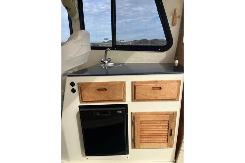  Yacht Photos Pics 2020 Eastern 27 Islander boat interior with sink, wooden cabinets, and window view.