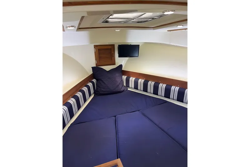  Yacht Photos Pics 2020 Eastern 27 Islander cabin interior with blue cushions and striped accents.