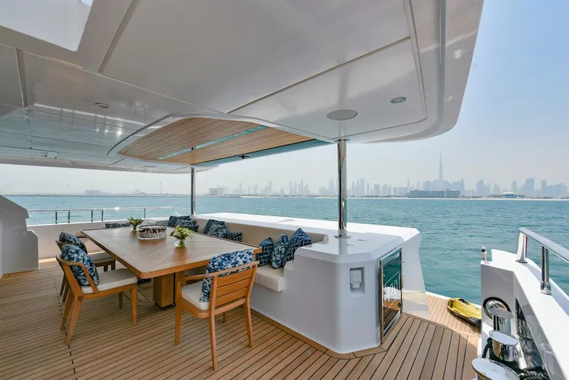  Yacht Photos Pics Luxurious 2026 Majesty 120 yacht deck with dining area, ocean view, and city skyline.