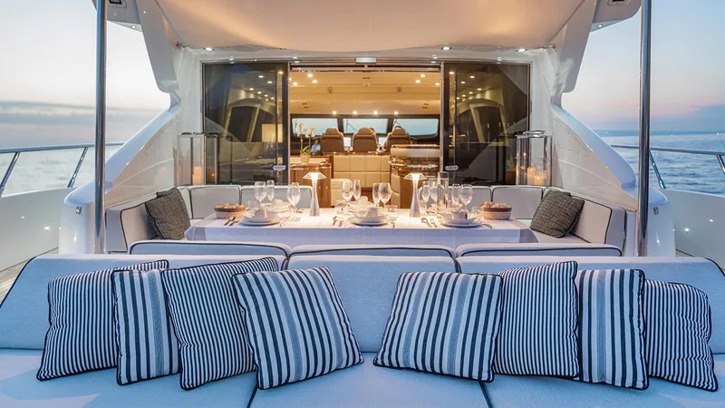 Deva I Yacht Photos Pics Luxurious 2008 Mangusta 92 yacht with elegant outdoor dining area and striped cushions at sunset.
