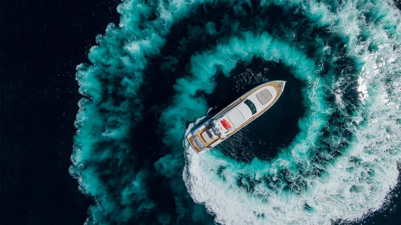 Deva I Yacht Photos Pics Aerial view of 2008 Mangusta 92 yacht creating circular wake in deep blue ocean.