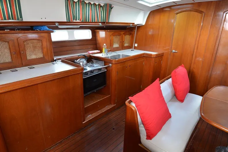  Yacht Photos Pics Interior of 1997 Beneteau Oceanis 461 yacht with wooden cabinetry and red-cushioned seating.
