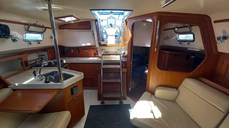 Sunny Girl Yacht Photos Pics Interior of 2004 Island Packet 370 sailboat with kitchen, seating, and wooden finishes.