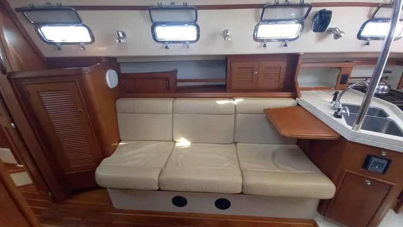 Sunny Girl Yacht Photos Pics Interior of 2004 Island Packet 370 sailboat with beige seating and wooden cabinetry.