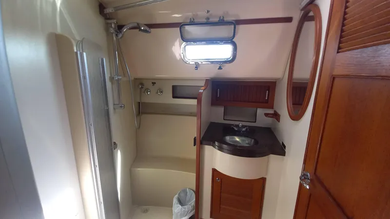 Sunny Girl Yacht Photos Pics 2004 Island Packet 370 yacht bathroom with shower, sink, and wooden cabinetry.