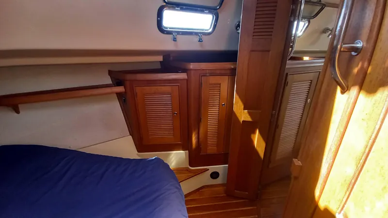 Sunny Girl Yacht Photos Pics Interior cabin of 2004 Island Packet 370 sailboat with wooden cabinets and blue bedding.