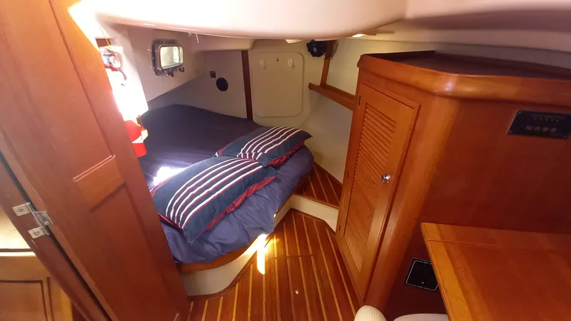 Sunny Girl Yacht Photos Pics Cozy cabin interior of 2004 Island Packet 370 sailboat with wooden finishes and striped bedding.