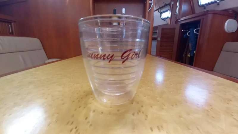 Sunny Girl Yacht Photos Pics Clear tumbler with "Sunny Girl" text on a wooden table inside a 2004 Island Packet 370 yacht.