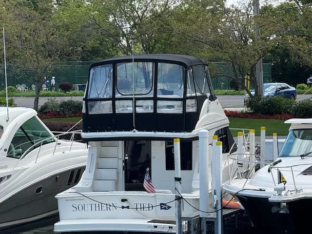  Yacht Photos Pics 2004 Silverton 34 Convertible yacht docked, featuring a covered upper deck and American flag.