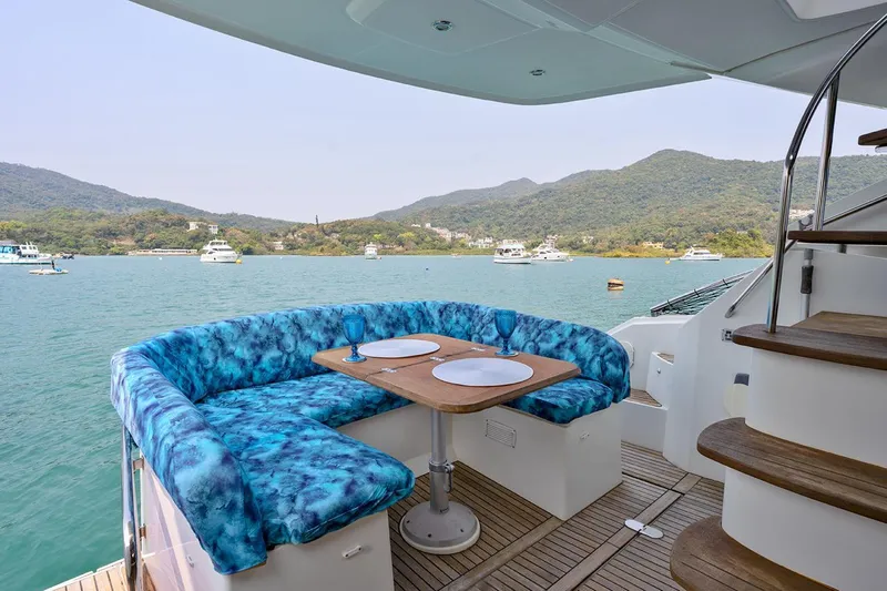  Yacht Photos Pics Luxurious Beneteau Monte Carlo 47 Fly yacht deck with blue seating, scenic water view.